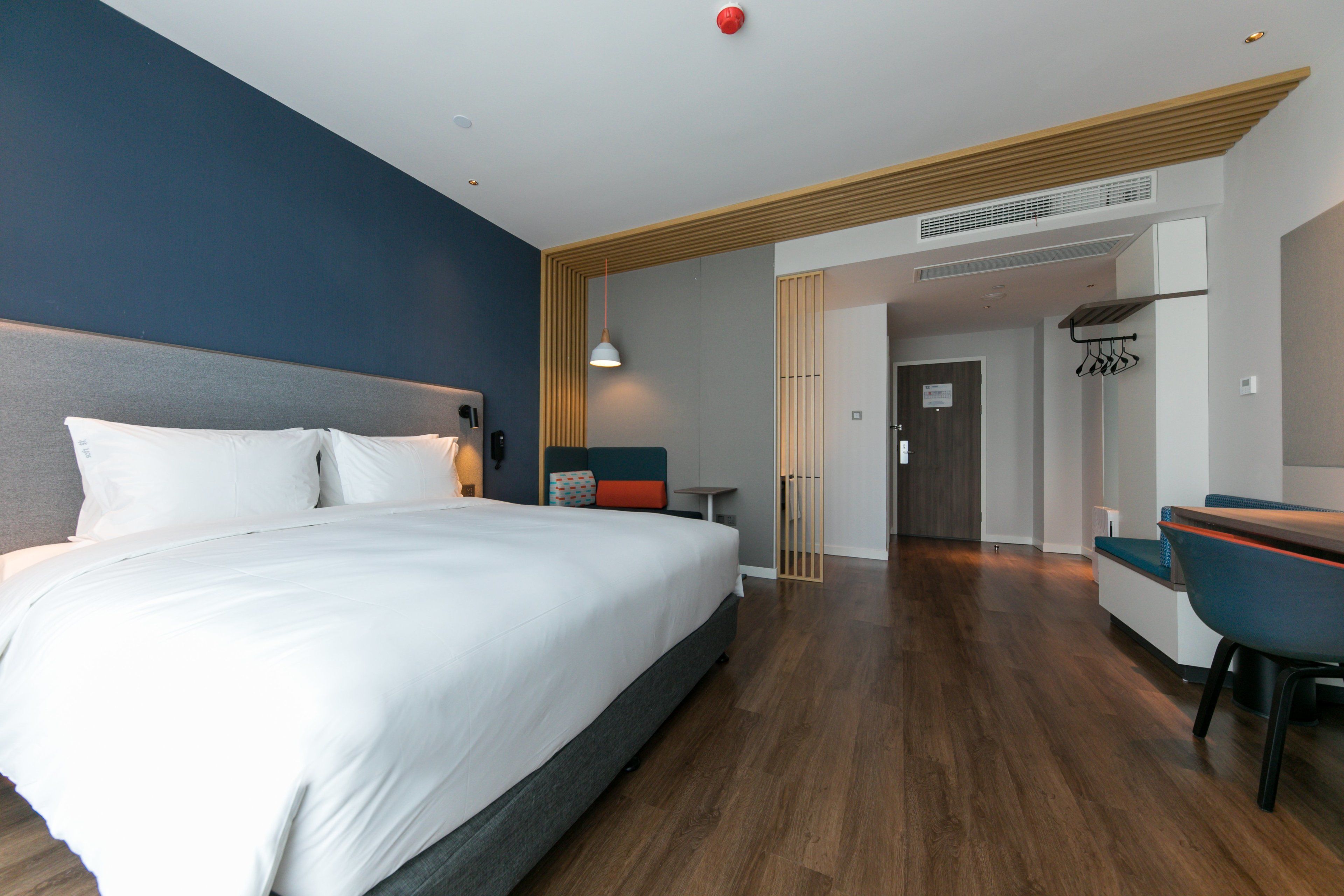 A modern hotel room with a large bed, a desk, and a seating area.