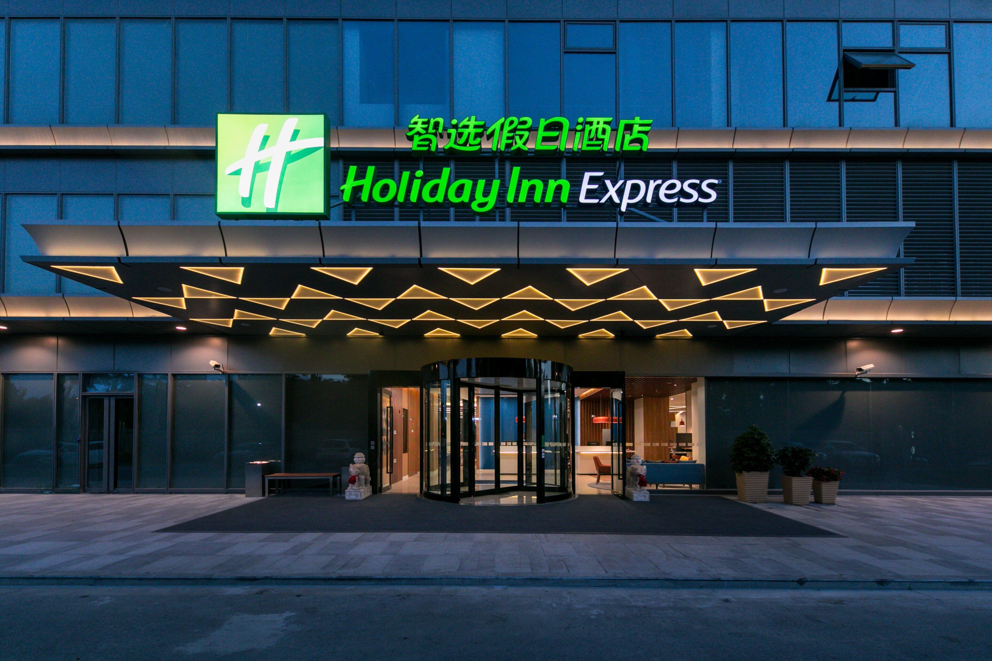 A Holiday Inn Express hotel entrance with a glass facade and a geometric roof design.