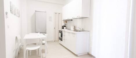 Een koelkast, een oven, een kookplaat, kookgerei, borden en bestek