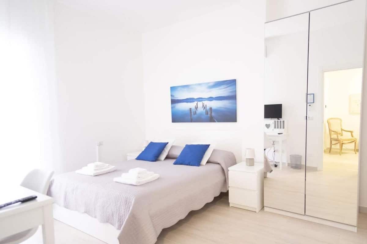 A modern bedroom with a bed, bedside tables, a TV, and a wardrobe.