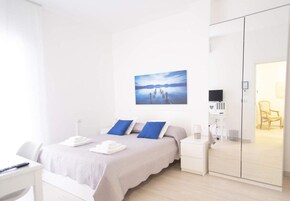 Una camera da letto moderna con un letto, comodini, televisione e armadio.