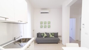 A modern kitchen with a built-in sink and a grey sofa with decorative pillows. - Casa Viviana - Bari Policlinico (Bari)