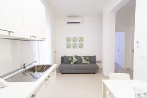 Una cucina moderna con lavello integrato e un divano grigio con cuscini decorativi.
