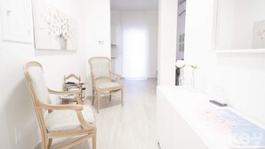 A bright, white room with two wooden chairs, a white table, and a painting on the wall. - Casa Viviana - Bari Policlinico (Bari)