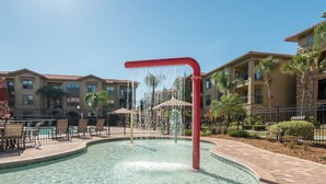 A swimming pool with a water feature, surrounded by lounge chairs and a covered seating area. - Quiet condo close to Disney World, fully furnished, No Resort Fee (Davenport)