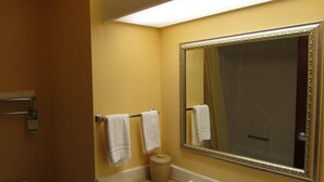 A bathroom with a large mirror, two towels hanging on a rack, a toilet, and a sink with a soap dispenser. - Executive Inn and suites, independent hotel (Wichita Falls)