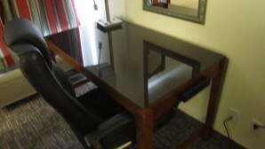 A conference room with a glass table, a black office chair, a small side table, and a mirror on the wall. - Executive Inn and suites, independent hotel (Wichita Falls)