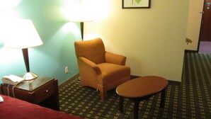 A hotel room with a bed, a chair, a small table, a lamp, and a framed picture on the wall. - Executive Inn and suites, independent hotel (Wichita Falls)
