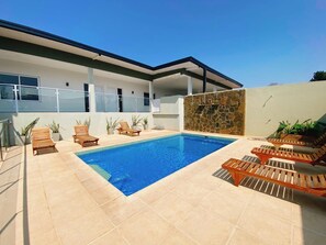 A modern pool area with a rectangular pool, wooden loungers, and a stone wall. - Aires de Cataratas (Puerto Iguazú)