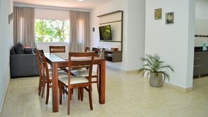 Una sala moderna con comedor, un sofá gris, una mesa de comedor de madera y una planta en maceta.