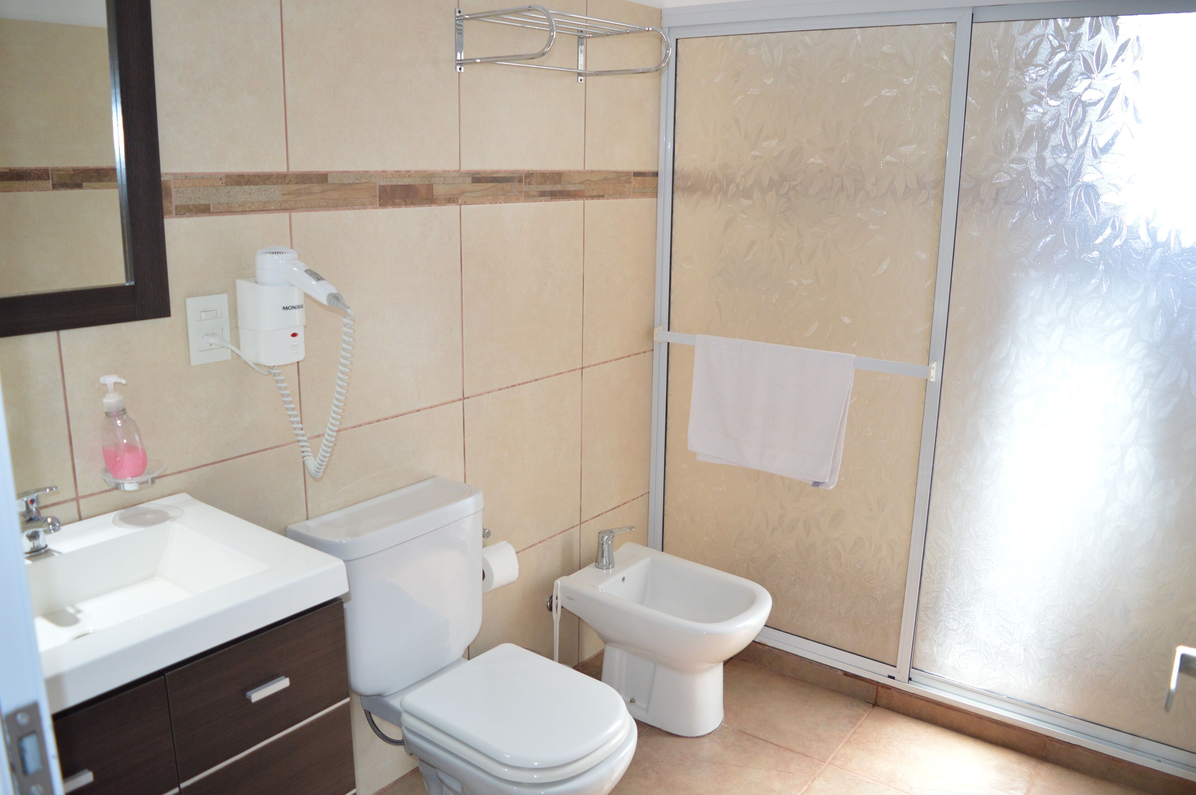 A bathroom with a toilet, bidet, sink, and mirror.