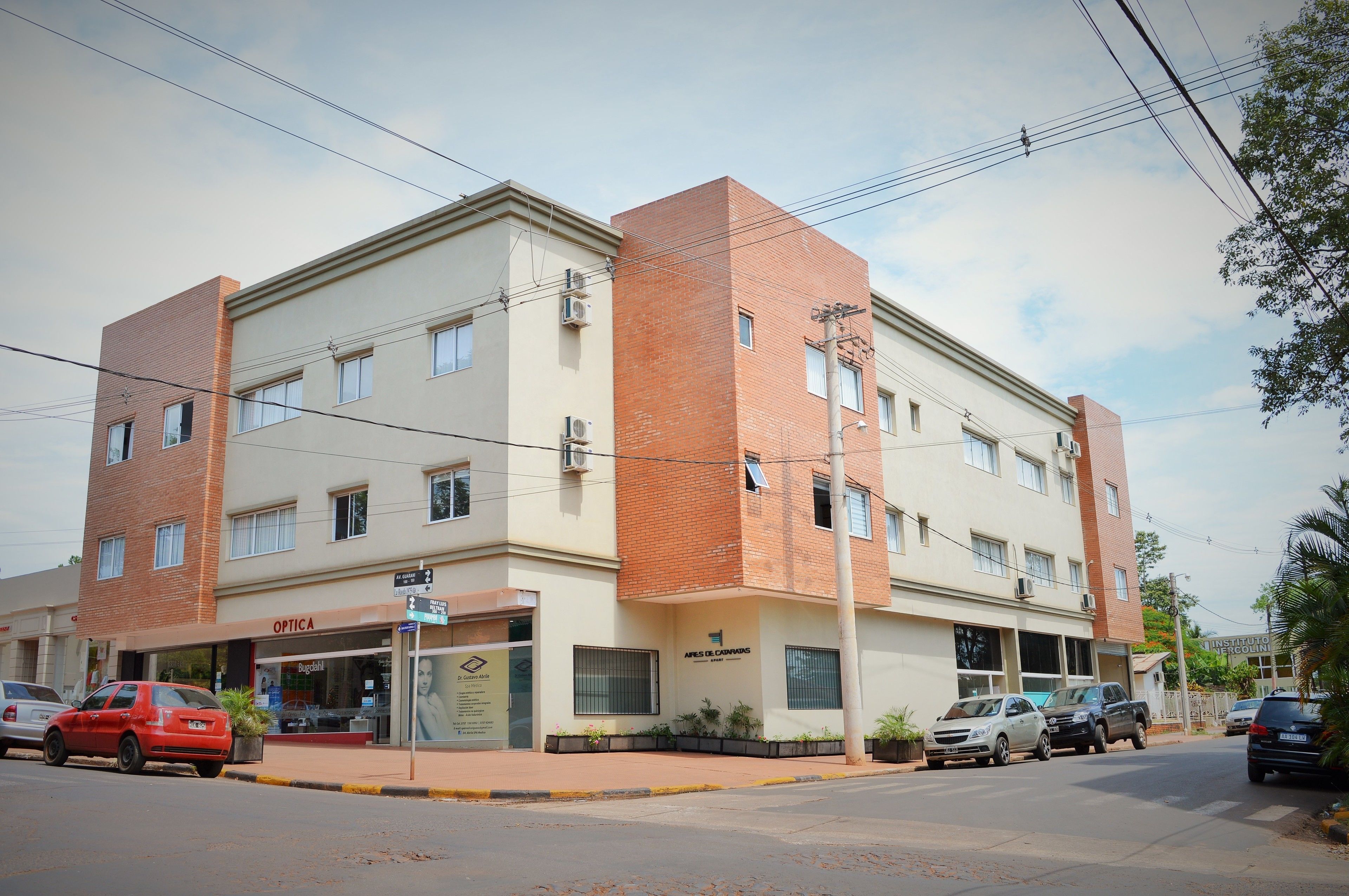 Un edificio de varios pisos con una óptica en la planta baja y un letrero de salón de belleza.