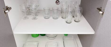 A storage unit with multiple shelves holding clear glassware and dishes.