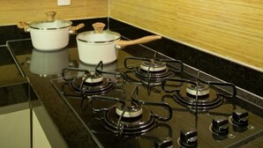 A kitchen with a gas stove, two pots, and a wooden backsplash. - Hotel Home Vacations (Natal)