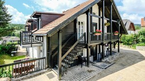 A traditional chalet with a steep roof, wooden balconies, and a stone pathway leading to the entrance. - Hotel Garni Zum Holzfäller (Wernigerode)