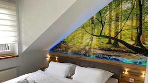 A bedroom with a bed, white bedding, and a large forest mural on the wall. - Hotel Garni Zum Holzfäller (Wernigerode)