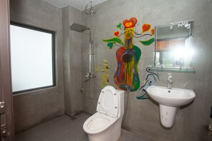A bathroom with a toilet, sink, shower, and a large window.