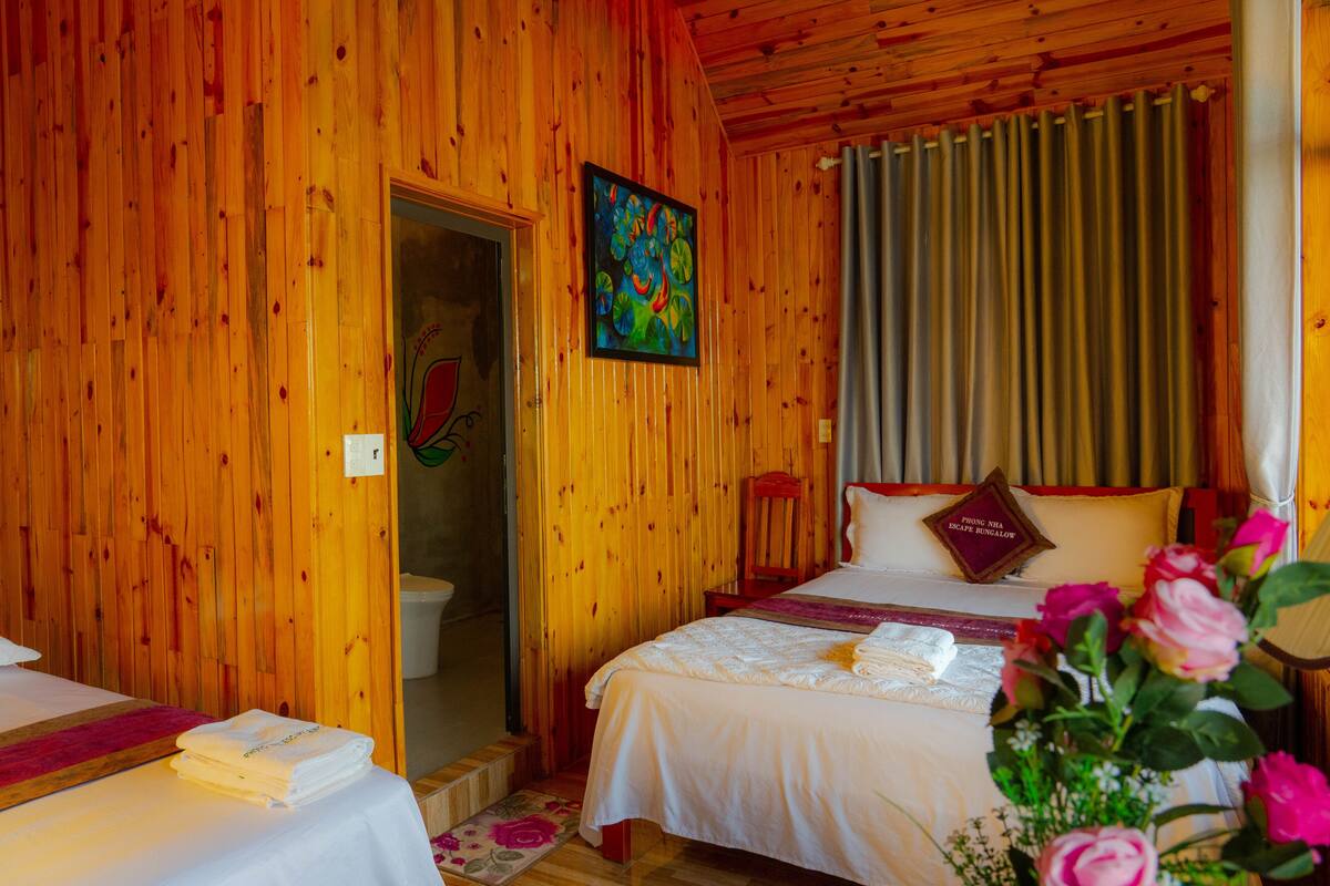 A wooden cabin-style room with two beds, a painting, and a curtain.