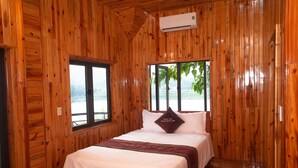 A wooden-paneled room with a bed, a window, and an air conditioning unit. - Phong Nha Escape Bungalow (Phong Nha)