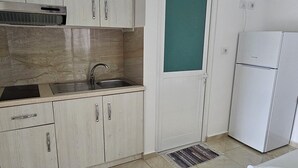 Una cocina compacta con fregadero, armarios y refrigerador.