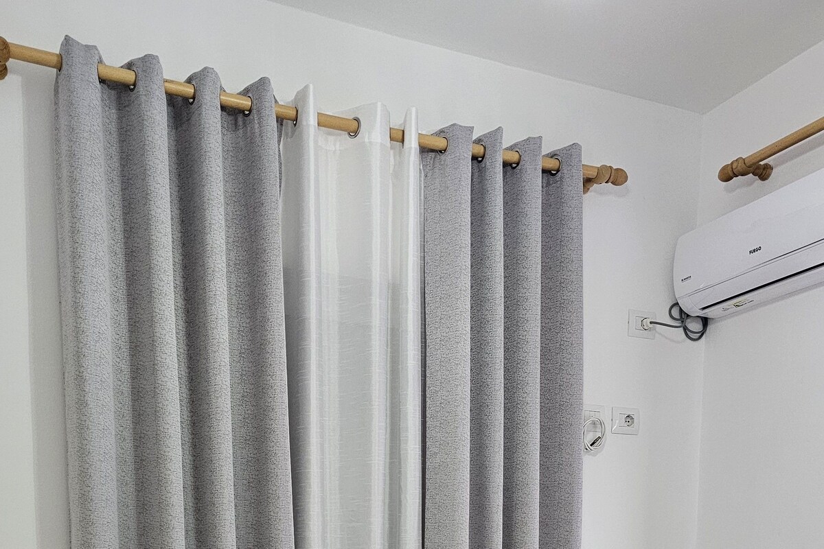 Ein Schlafzimmer mit einem Bett, einem Vorhang und einer Wand-Klimaanlage.