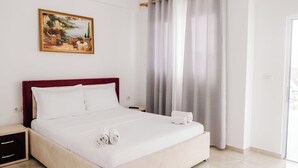 Habitación de hotel con cama, mesita de noche, un cuadro en la pared y vistas a través de la ventana.