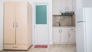 Una cocina compacta con un refrigerador blanco, un armario beige y una pequeña zona de fregadero.