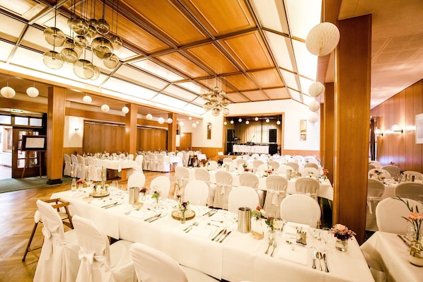 A banquet hall with round tables set for a formal event, featuring white tablecloths, chairs, and floral centerpieces. - Triple room - Landhotel Zur Eiche (Buxtehude)