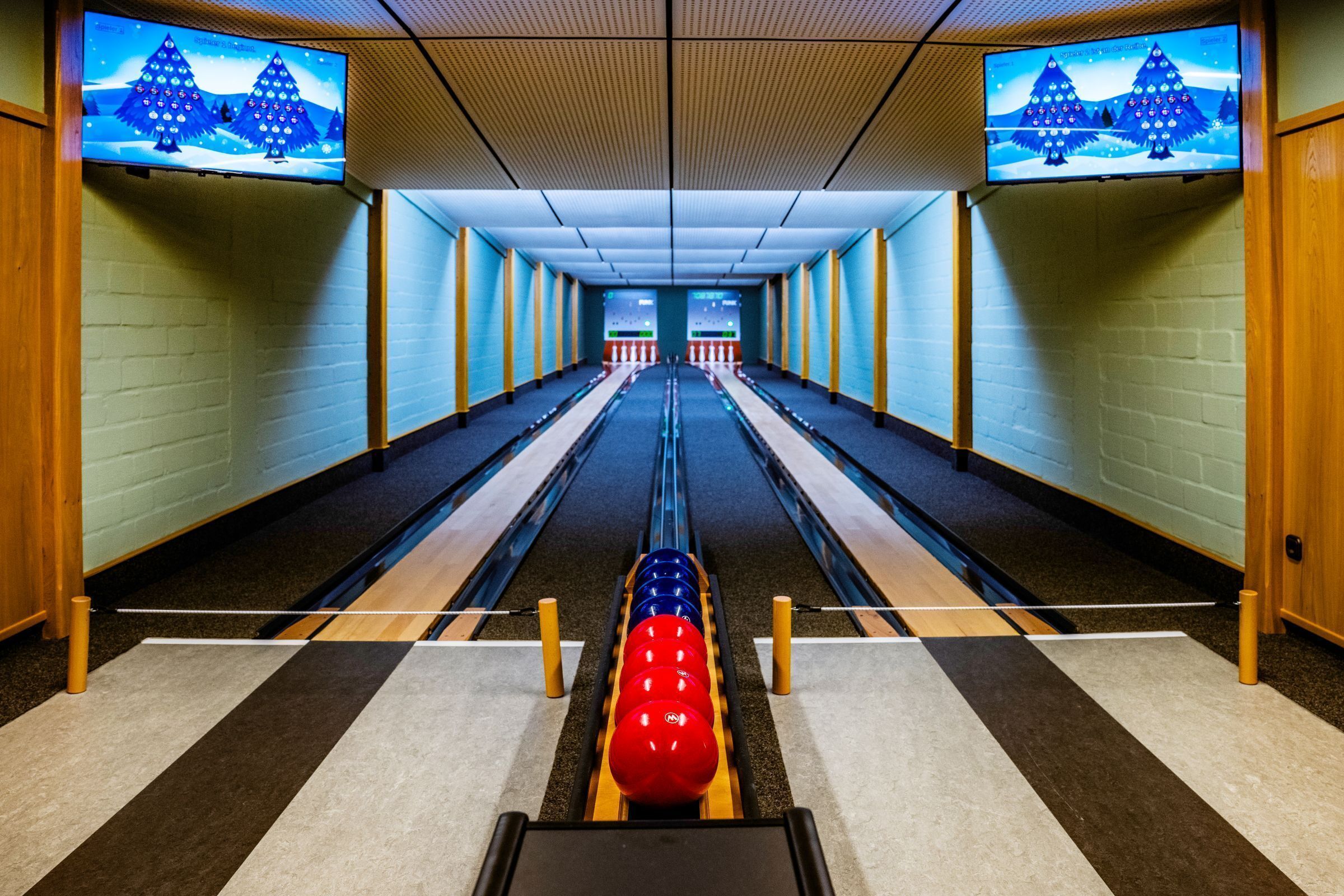 Une salle de bowling avec des pistes, des quilles et une boule de bowling.
