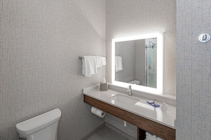 Une salle de bain moderne avec des toilettes blanches, un meuble-lavabo en bois doté d'un miroir et un mur orné d'un motif.