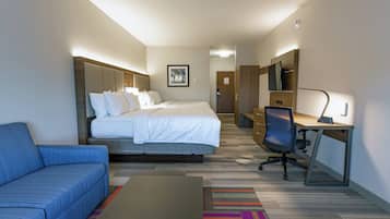 A hotel room with a bed, a desk, a chair, a sofa, and a TV.