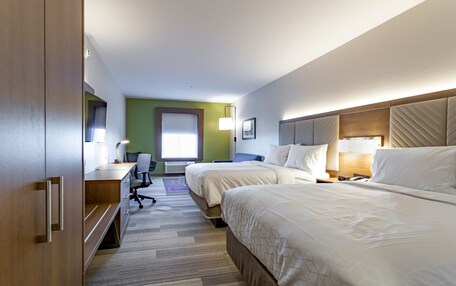 Habitación de hotel con dos camas, un escritorio, una silla y un ventanal grande.