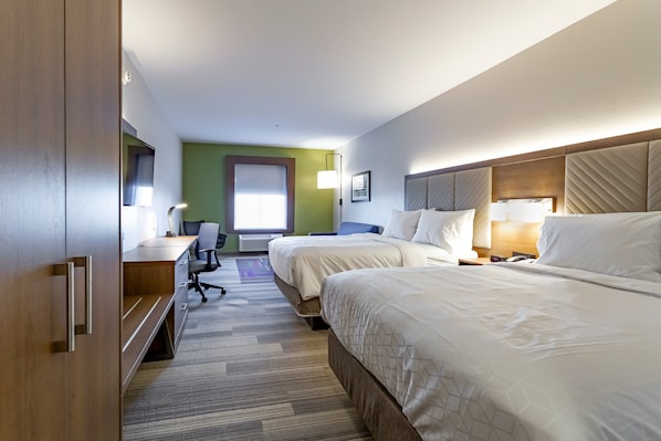 Une chambre d’hôtel avec deux lits, un bureau, une chaise et une grande fenêtre.