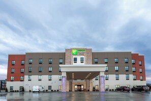 A hotel with a prominent 'Hilton Express' sign, a covered entrance, and a parking lot with vehicles.