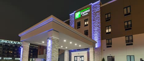 A Holiday Inn Express & Suites hotel with a covered entrance and a stone facade.