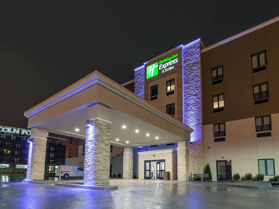 Ein Holiday Inn Express & Suites Hotel mit überdachter Eingangspartei und einer Sandsteinfassade.