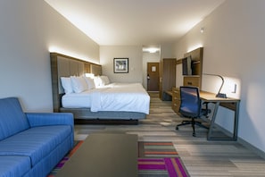 Une chambre d’hôtel comprenant un lit, un bureau, une chaise, un canapé et un téléviseur.