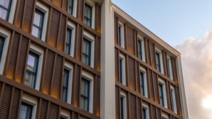 Un edificio moderno con una fachada de ventanas dispuestas en cuadrícula y listones horizontales marrones.