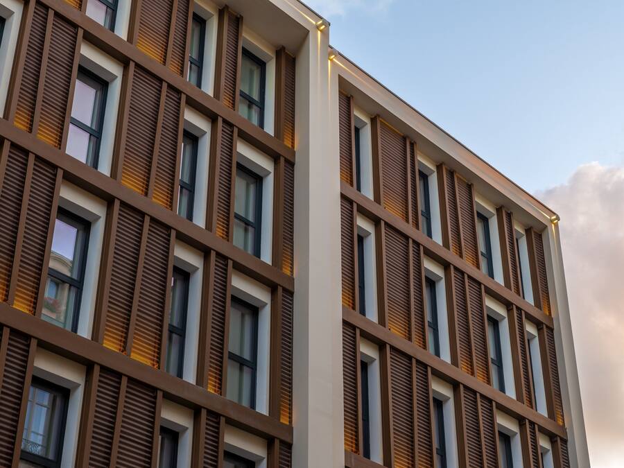 Um edifício moderno com uma grade de janelas e ripas horizontais castanhas.