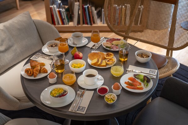A breakfast table with various food items, a cup of coffee, and a glass of orange juice. - Hotel Villa KOEGUI Bayonne (Bayonne)