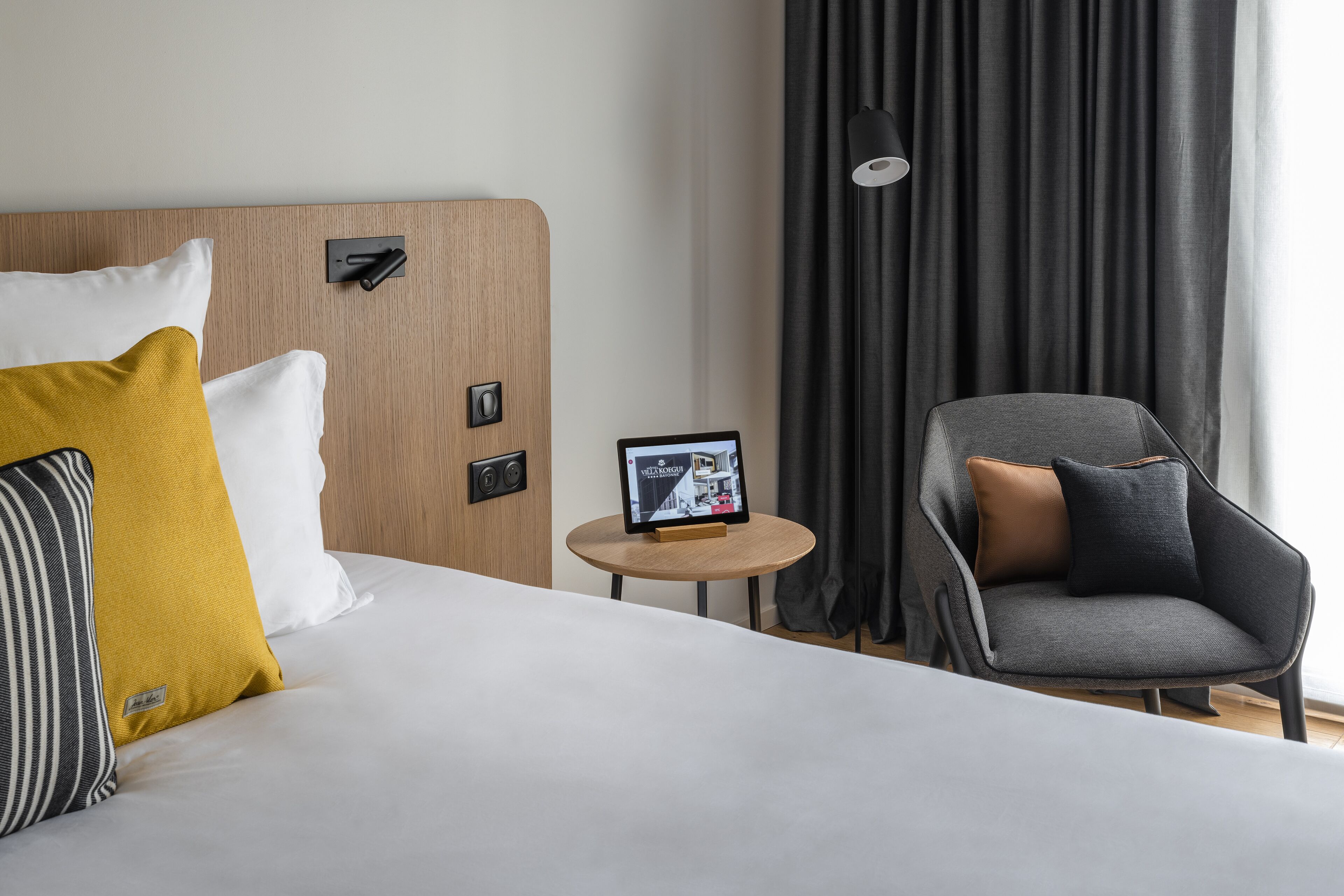 Een hotelkamer met een bed, nachtkastje, stoel en uitzicht.
