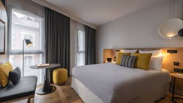 Une chambre d’hôtel moderne avec un grand lit, un canapé, une petite table et une lampe.