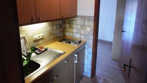 Cocina compacta con armarios de madera, un lavamanos de acero inoxidable y salpicadero de azulejos.
