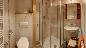 Uma casa de banho moderna com chuveiro em cabine de vidro, sanita e lavatório.