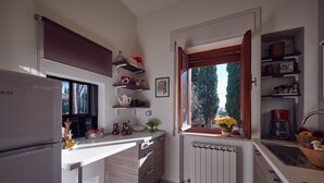 A modern kitchen with a built-in refrigerator, a window with a view of trees, and a variety of kitchen items on the countertops. - Le Balze Charming Apartment with private veranda, 10 min from Perugia Centre (Perugia)