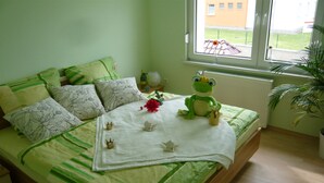 A neatly made bed with a green and white bedspread, a frog plush toy, and decorative items on the bed. - APARTMENT II - PUMMPÄLZHOF (Bad Salzungen)
