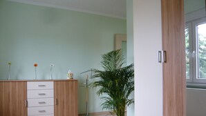 A room with a wooden cabinet, a potted plant, and a window. - APARTMENT II - PUMMPÄLZHOF (Bad Salzungen)