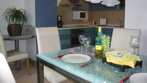 A modern kitchen with a microwave, stove, and a dining area with a table set for two. - APARTMENT II - PUMMPÄLZHOF (Bad Salzungen)