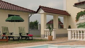 A swimming pool area with lounge chairs and an umbrella.