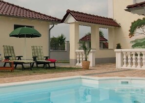 Un área de piscina con sillones de playa y una sombrilla.